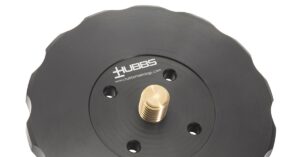 A black round machined part with a brass threaded center, scalloped edges, and 'HUBBS' in white lettering.