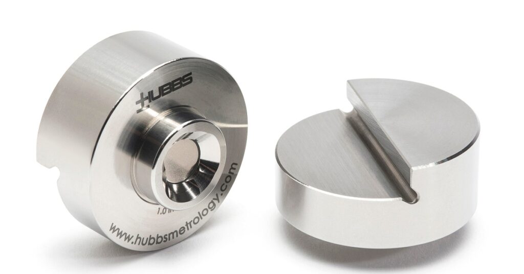 Two silver machined metal parts with engraved lettering, circular centers, curved cutouts, and brushed surfaces.